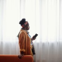 窓辺でスマホを手に考え込む人の様子